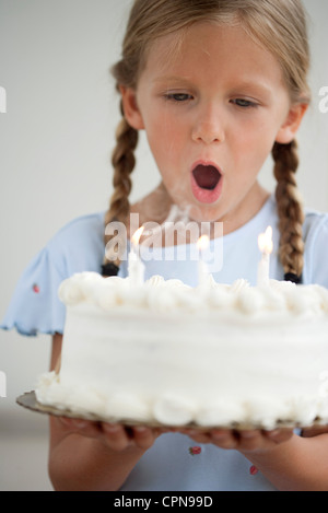 Ragazza soffiando le candeline sulla torta di compleanno Foto Stock