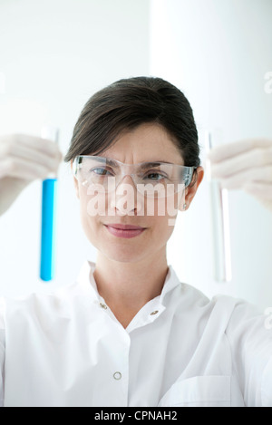 Scienziato Azienda fino in provette contenenti liquido Foto Stock