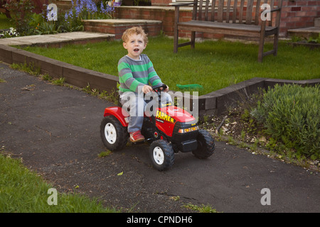 Ragazzo di tre anni in giro su un trattore giocattolo, Alresford, Hampshire, Inghilterra, Regno Unito. Foto Stock