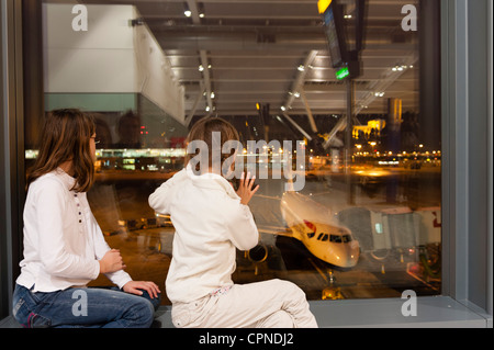 Bambini Watch dall' aeroporto finestra di terminale come equipaggio di volo preparare aereo commerciale per l'imbarco Foto Stock