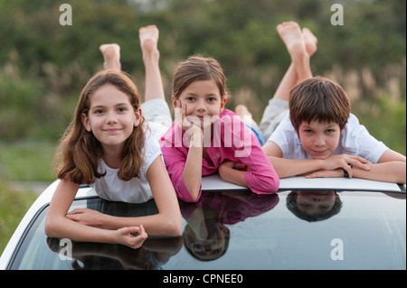 I fratelli giacente sulla sommità del tetto auto, ritratto Foto Stock