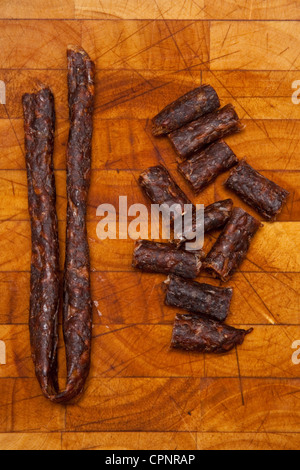South African piccante Peri peri drywors (salsiccia secca a scatti) su una tavola di legno blocco di trinciatura. Foto Stock