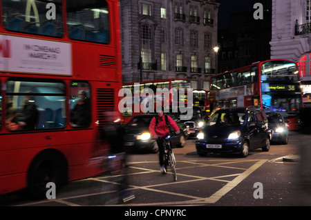 I ciclisti negoziando traffico di Londra di notte Foto Stock