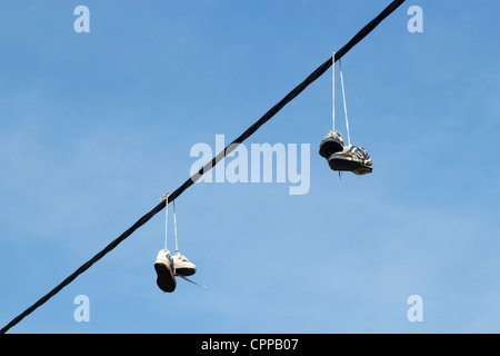 Due coppie di formatori scarpe running appesa a una linea telefonica. Foto Stock