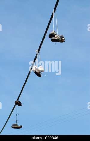 Tre coppie di formatori scarpe running appesa a una linea telefonica. Foto Stock