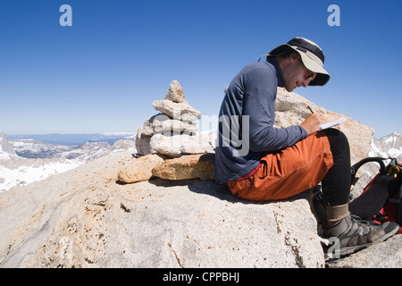 Un uomo di firmare il registro del vertice sulla vetta del Monte Merriam Foto Stock