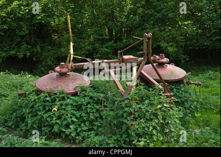 Vecchio rastrello fieno circondato da ortiche in un campo sul telecomando farm a Llanddewi Fach Mid-Wales POWYS REGNO UNITO Foto Stock