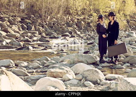 Un uomo e una donna in piedi sulle rocce circondato da un torrente di montagna Foto Stock