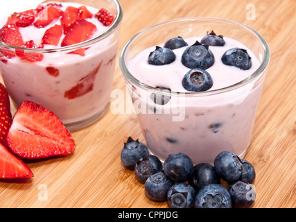 Yogurt misti (fragola e mirtillo) su sfondo di legno Foto Stock