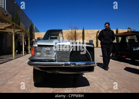 Un uomo Giordano ispeziona una vecchia installazione di un'auto Mercedes-Benz tagliata a metà esposta all'ingresso del museo dell'automobile reale nel Parco Nazionale di al Hussein. Amman Jordan Foto Stock