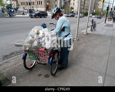 Una donna con un cestello di supporto sul suo triciclo di raccolta acqua in plastica bottiglie, lattine, tazze per il riciclaggio a Montreal Canada KATHY DEWITT Foto Stock