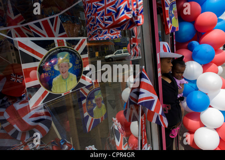 La madre e il bambino con patriottici bunting, bandiere, palloncini e royal memorabilia sul display prima che la regina del Giubileo di diamante in una Londra sud vetrina. Foto Stock