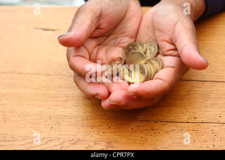 Una persona anziana holding £1 monete in entrambe le mani Foto Stock