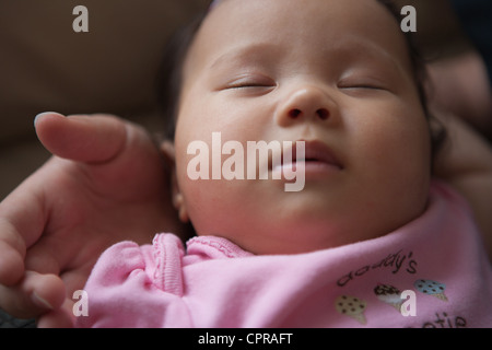 Bambino di quattro mesi ragazza, metà giapponese, metà caucasica, dormire in Gemelli il suo braccio, vicino. Foto Stock