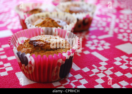 Muffin appena sfornati fatta con le carote e le mandorle in rosso bicchieri di carta in bianco e lo sfondo rosso Foto Stock
