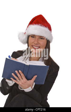Giovane donna con Santa's hat prendendo appunti circa la desiderata regali di Natale. Foto Stock