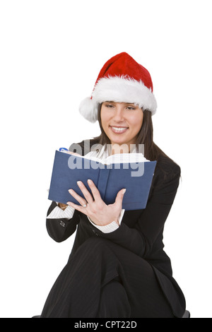 Giovane donna con Santa's hat prendendo appunti circa la desiderata regali di Natale. Foto Stock