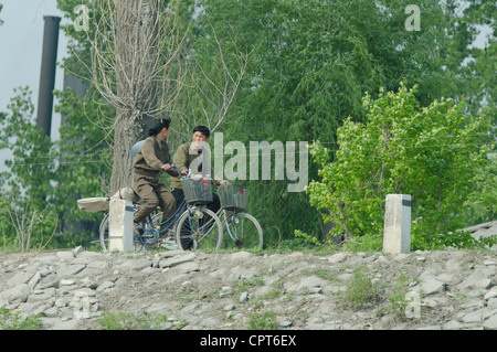 JI'an, Jilin, Cina; 20/05/2012. Un nord coreano l uomo e la donna in bicicletta lungo le rive del fiume Yalu. Foto Stock