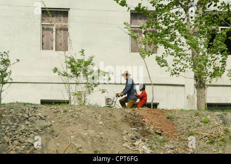 JI'an, Jilin, Cina; 20/05/2012. Un nord coreano è visto alla guida della sua bicicletta lungo le rive del fiume Yalu. Foto Stock