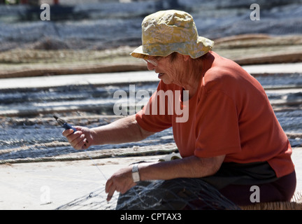 Donna che ripara le reti da pesca Cambrils Costa Dorada Spagna Foto Stock