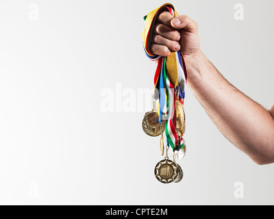 Uomo maturo holding medaglie d oro contro uno sfondo bianco Foto Stock