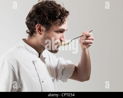 Lo chef cucina dal cucchiaio contro uno sfondo bianco Foto Stock