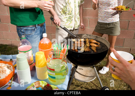 Uomo in cucina con gli amici a barbecue Foto Stock