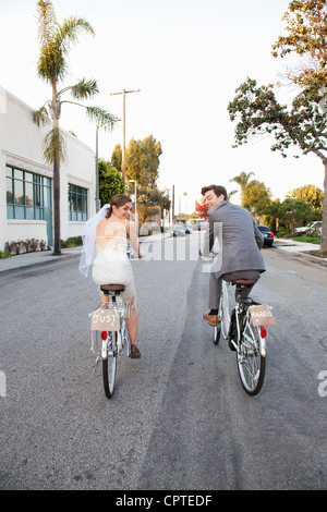 Giovane sposa giovane escursioni in bicicletta lungo la strada, vista posteriore Foto Stock