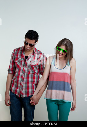 Coppia giovane indossando occhiali da sole e ridere, studio shot Foto Stock
