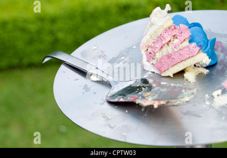 Un pezzo di torta di nozze su un supporto in un giardino. Foto Stock