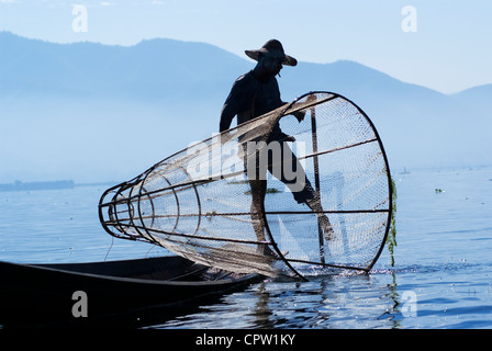 I pescatori nel Lago Inle fare una vita utilizzando una coop-come trap con net per la cattura di pesci e sono noti per le loro gambe stile di canottaggio Foto Stock