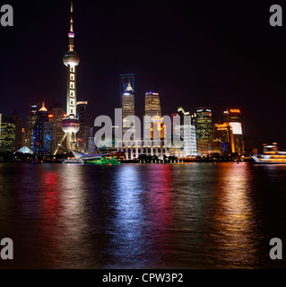 Luminose luci notturne di Pudong alte torri si riflette nel fiume Huangpu con barche di Shanghai Repubblica Popolare Cinese Foto Stock