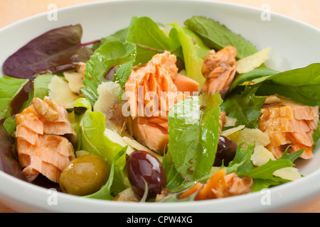 Legno di salmone affumicato in fiocchi in un insalata di foglie di lattuga, olive, parmigiano e condimento balsamico. Foto Stock