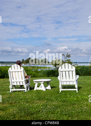 Patio sedie a fianco della Chesapeake Bay si affaccia su St Michaels harbour con maschio senior Foto Stock