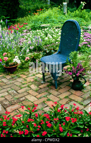 Blu sedia di vimini in mattone antico giardino con fiori che sbocciano in giugno, Missouri USA Foto Stock