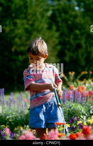 I giovani afghani ragazzo americano abbeveraggio coloratissimi fiori estivi con tubo flessibile, Missouri USA Foto Stock