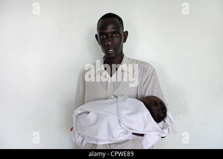 Un richiedente asilo dal Sudan tenendo un bambino in Israele Foto Stock