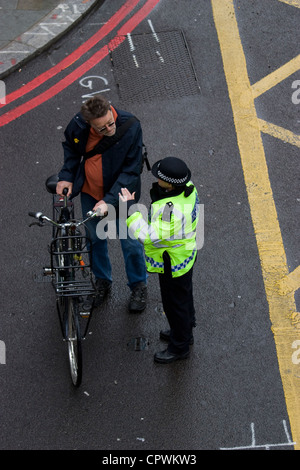 Agente di polizia donna che parla con un ciclista in London Street, Regno Unito Foto Stock