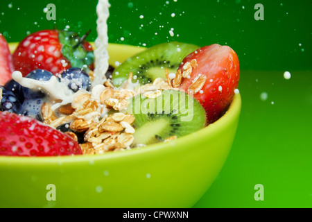 Ciotola con muesli e frutti di bosco freschi e frutta con gli spruzzi di latte Foto Stock