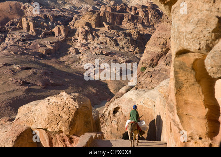 Uomo a cavallo di asino in antiche rovine di Petra, Giordania (Patrimonio Mondiale dell'UNESCO) Foto Stock