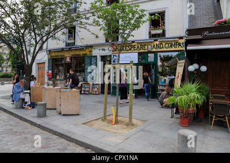 La libreria Shakespeare and Company, Parigi. Un uomo si siede su una concreta bollard e legge un libro in brossura in un pomeriggio di primavera. Foto Stock