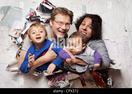 La famiglia felice rompendosi attraverso una parete Foto Stock