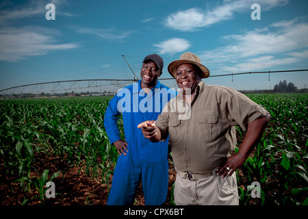 L'agricoltore nero sorge sorridente in un campo di coltivazione con il suo lavoratore Foto Stock