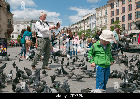 Gridando bambino tra piccioni in affollata piazza principale del mercato, Cracovia in Polonia. Foto Stock