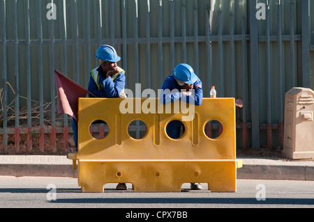 Due lavoratori edili in piedi accanto ad una barriera di traffico Foto Stock