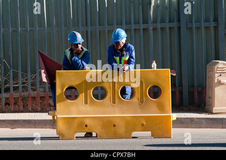 Due lavoratori edili in piedi accanto ad una barriera di traffico Foto Stock