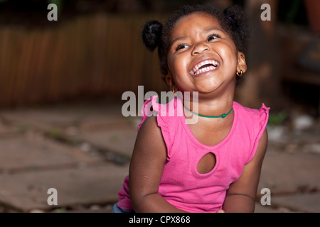 Giovane femmina nera bambino seduto sul pavimento ridendo Foto Stock