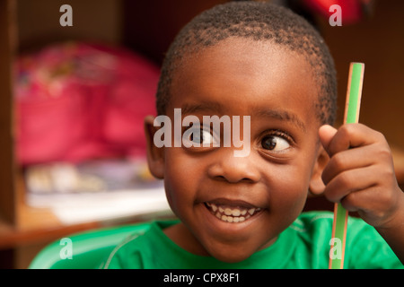 Bambino tenendo una matita pastello, sorridente Foto Stock