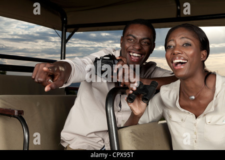 Un africano giovane ridere insieme durante la visualizzazione del gioco in una riserva di caccia Foto Stock