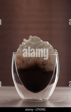 Un vetro trasparente di cioccolata calda coperta con panna montata. Foto Stock
